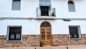 A building with a central wooden door, stone lower walls, and two windows with metal bars. - Tourist House in the center of Vilafamés (Vilafamés)