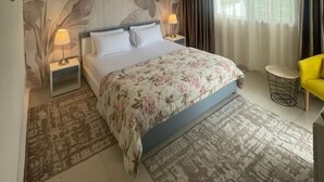 A bedroom with a bed, two bedside tables, a lamp, a chair, and a large window with curtains. - La Vida Villa Alcudia Simr-Fnideq (Fnideq)