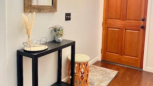 A wooden door, a console table with a mirror, a wall-mounted light, and a small stool. - Purified pool-private back yard-family  (Tucson)