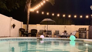 An outdoor pool area with string lights, chairs, and a grill. - Purified pool-private back yard-family  (Tucson)
