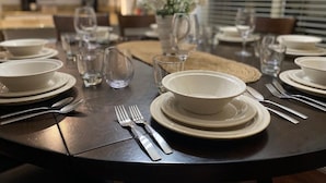 A dining table set with white plates, bowls, and cutlery, with a vase of flowers in the center. - Purified pool-private back yard-family  (Tucson)