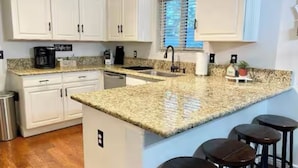 A kitchen with white cabinets, a granite countertop, a sink, and a window with blinds. - Purified pool-private back yard-family  (Tucson)