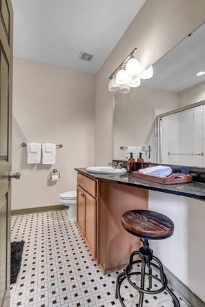 Bagno con lavandino, specchio, porta asciugamani, water e pavimento decorato.