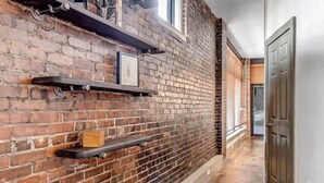 A hallway with exposed brick walls, metal shelves, and a polished concrete floor. - Modern-Industrial 2B Townhouse Close to DT! (Jacksonville)