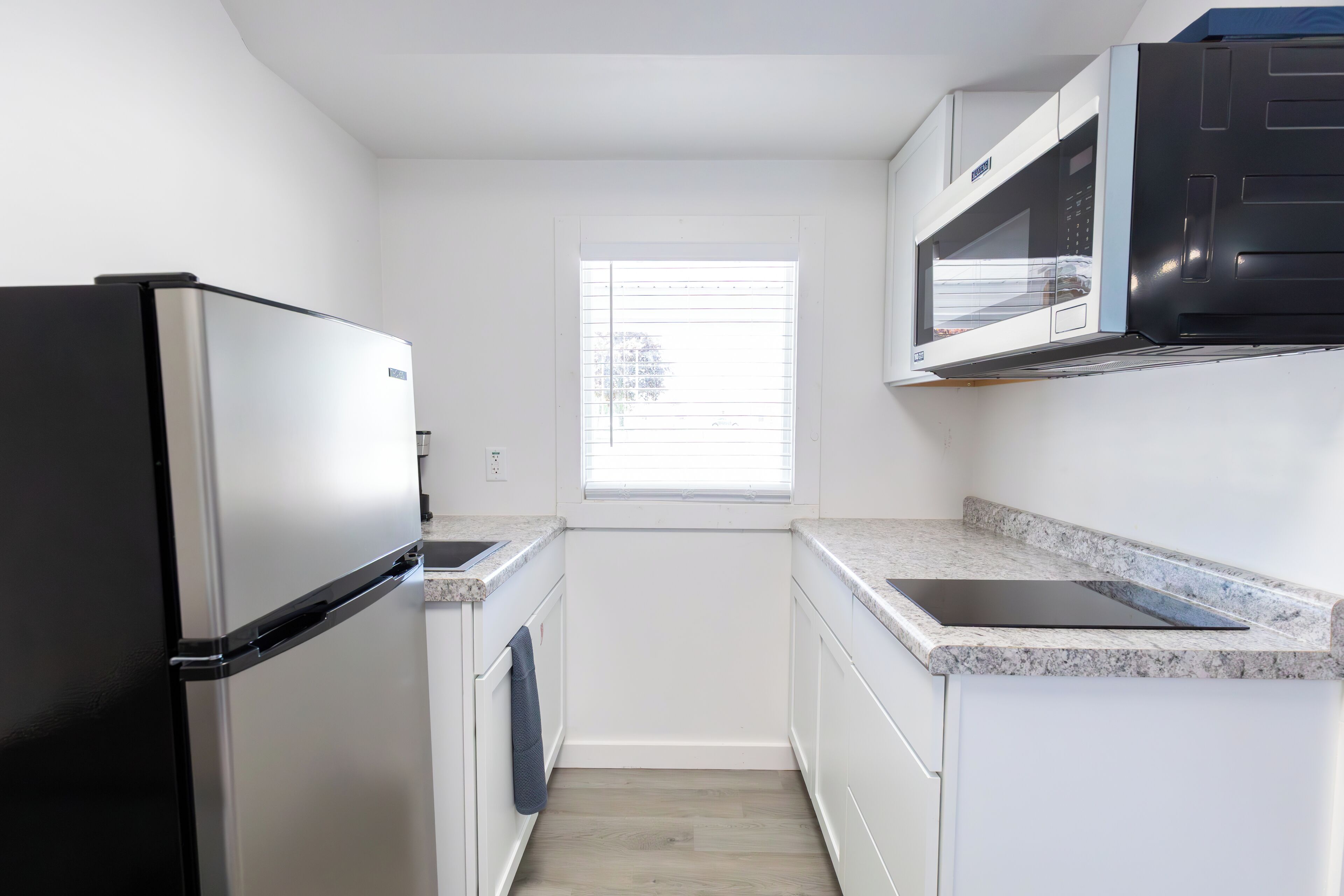 A compact kitchen with a refrigerator, microwave, and sink.