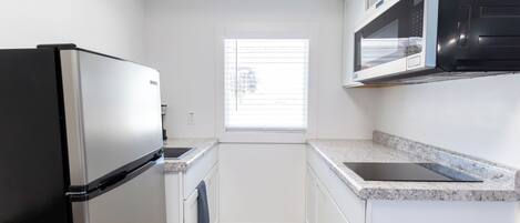 A compact kitchen with a refrigerator, microwave, and sink.