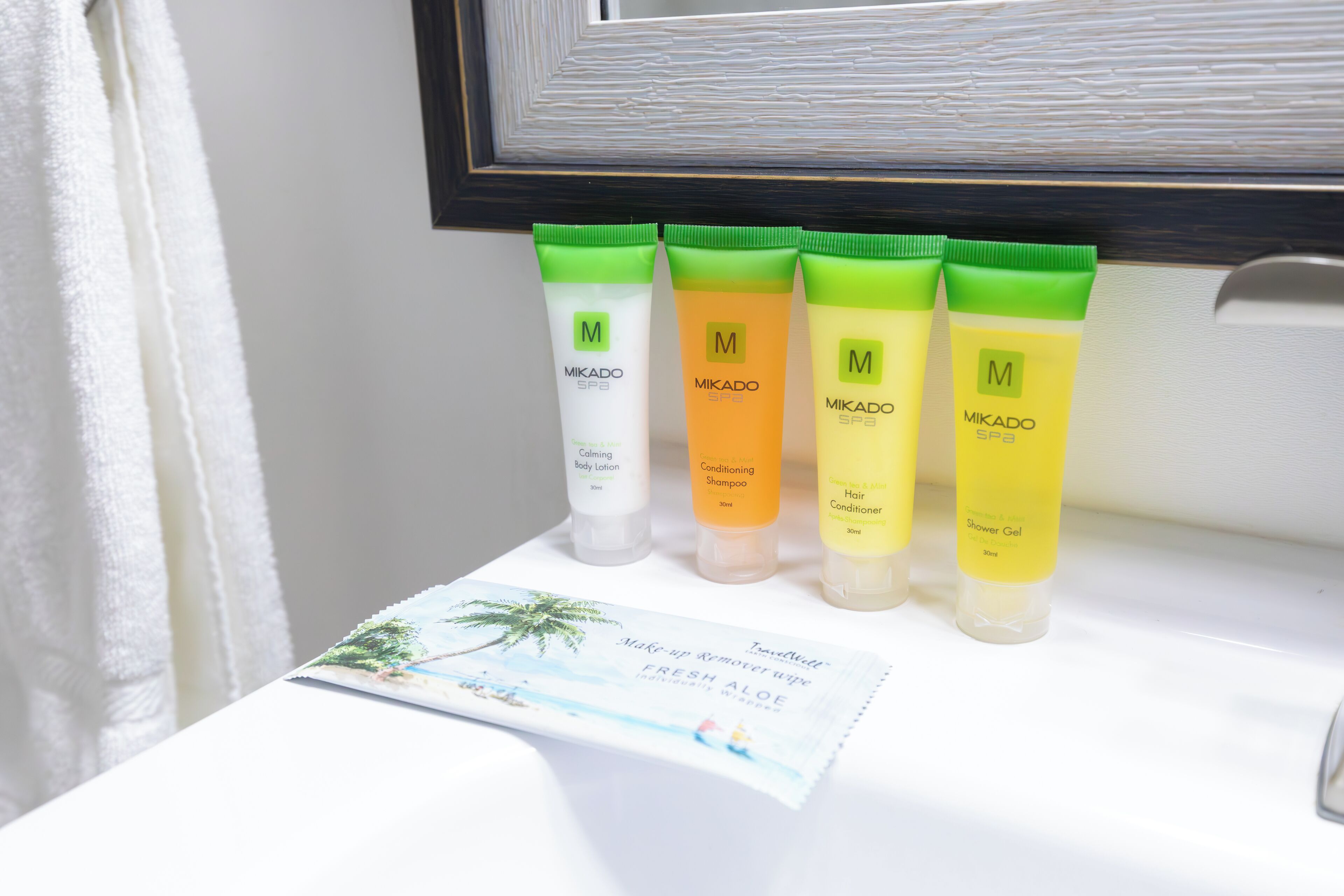 A bathroom counter with four Mikado SPF3 skincare products and a travel brochure.