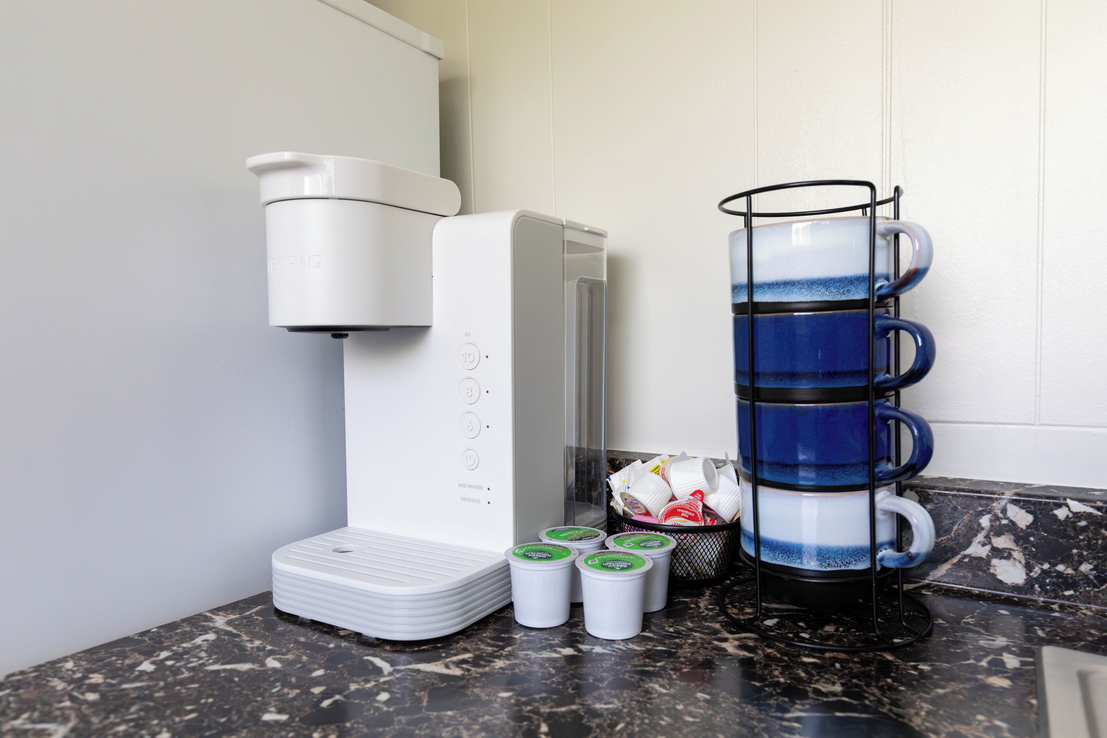 Une machine à café, une pile de tasses et un porte-tasses sur un comptoir.