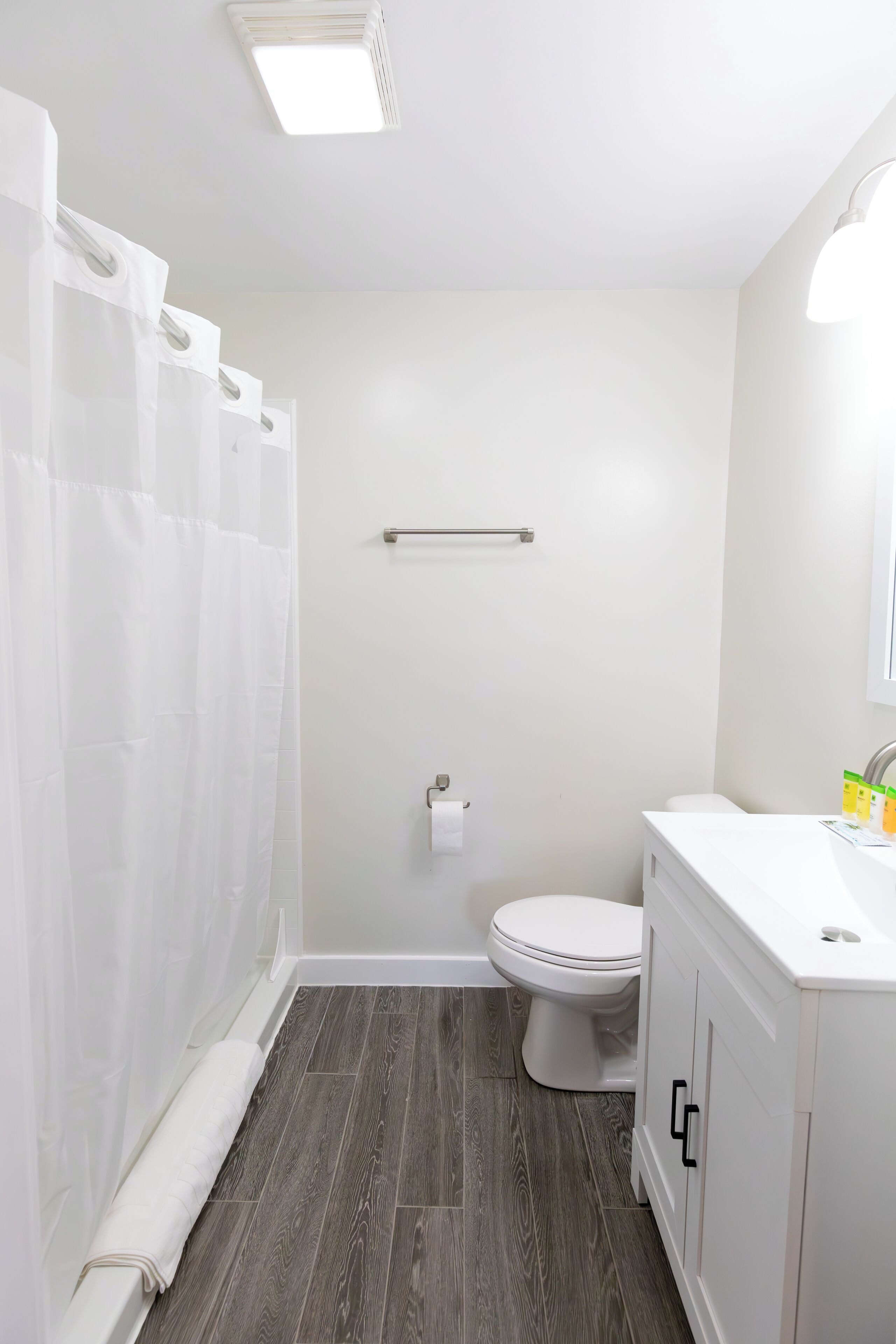 A bathroom with a white toilet, a white sink with a mirror, and a shower curtain.