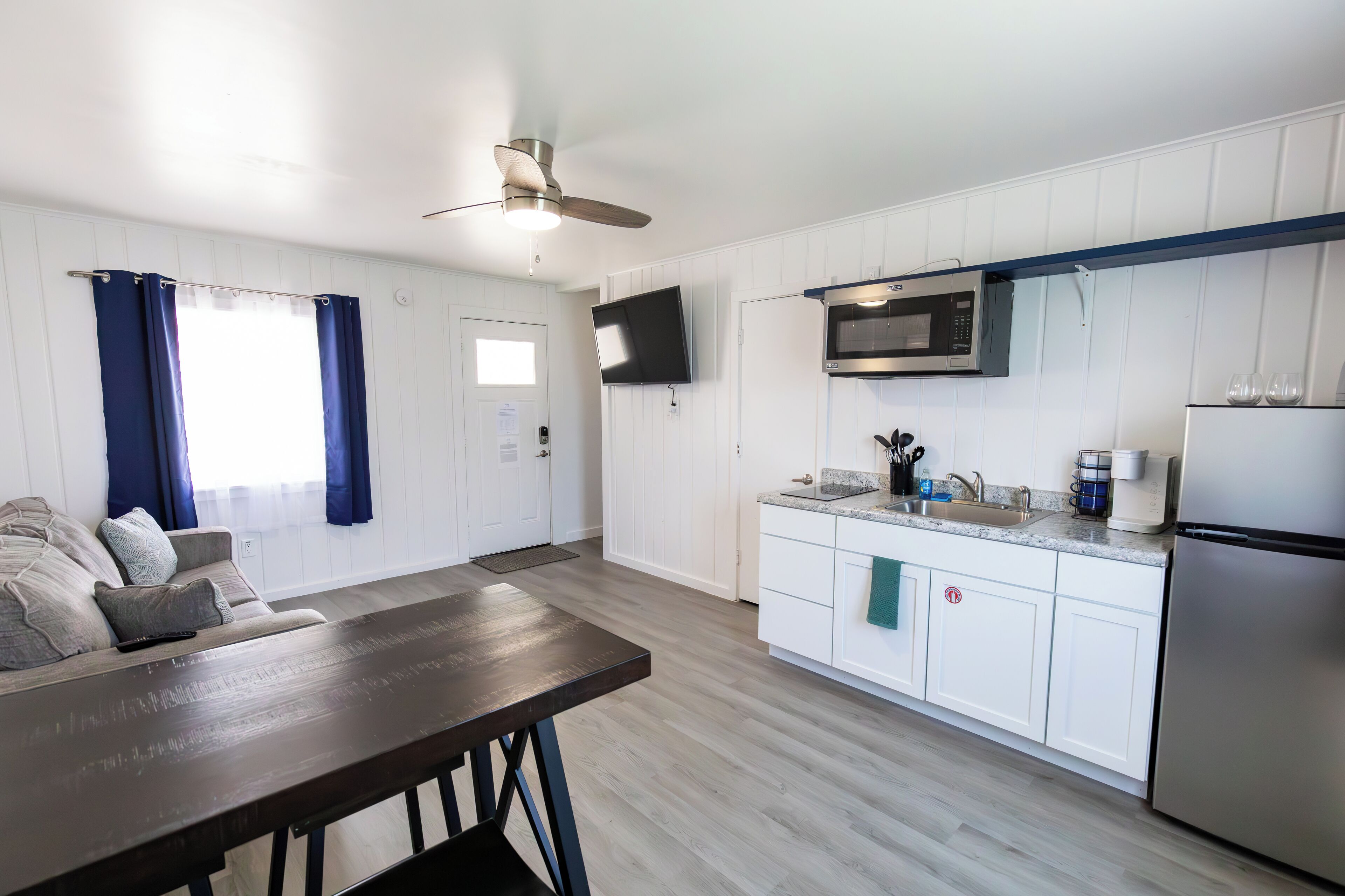 A modern kitchen with white cabinets, a microwave, and a refrigerator.