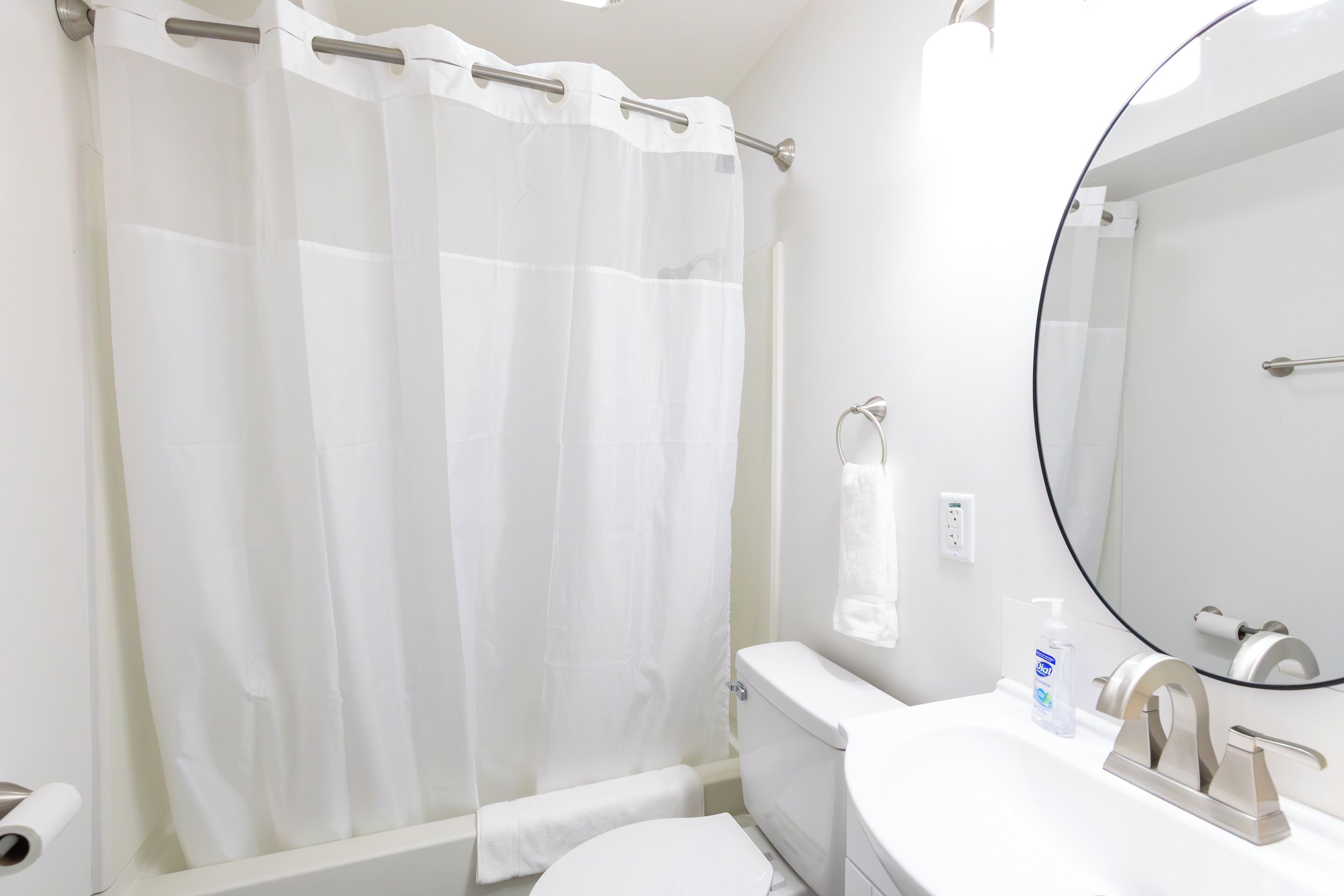 A bathroom with a white toilet, a sink with a mirror, and a shower curtain.