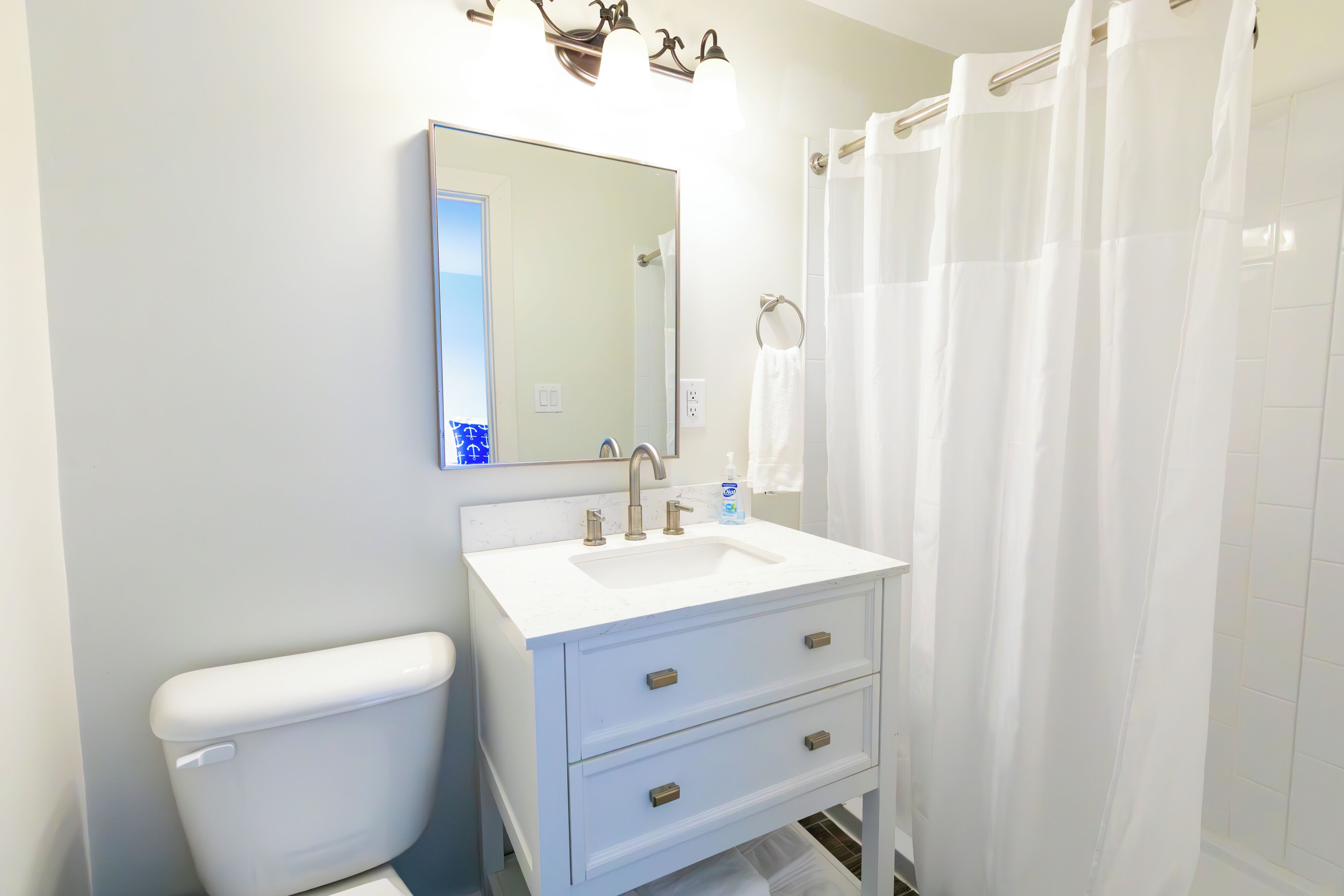 A bathroom with a white sink, mirror, and toilet.