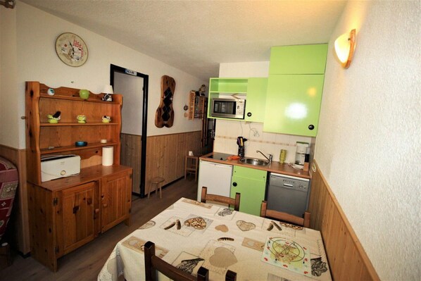 Eine kleine Küche mit Holzschränken, einer Mikrowelle und einem Geschirrspüler.