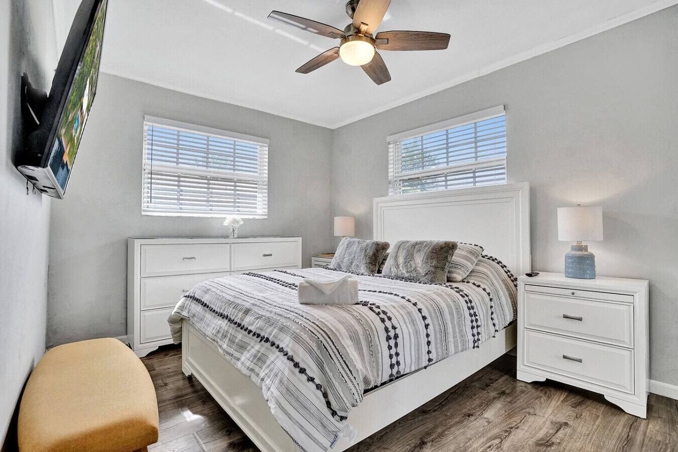 A bedroom with a bed, nightstands, a bench, and a ceiling fan.