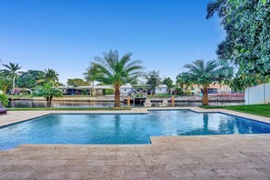 Relax by the serene pool surrounded by lush greenery and palm trees.