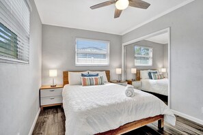 Relax in this serene bedroom with a large bed, wooden headboard, and ceiling fan.