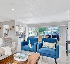Relax in this stylish living room with a sofa, armchair, and coffee table, offering a view of the outdoors.