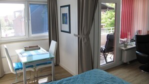 A room with a bed, a desk with a chair, a radiator, and a window with curtains. - Ostseeperle Modernly furnished with swimming pool  (Dahme)