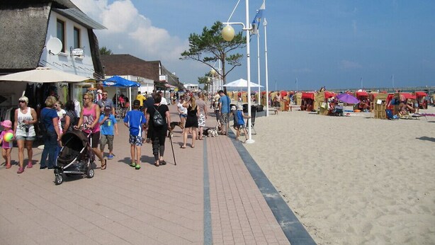 A beachside promenade with a paved walkway, beach umbrellas, and beachgoers. - Ostseeperle Modernly furnished with swimming pool  (Dahme)