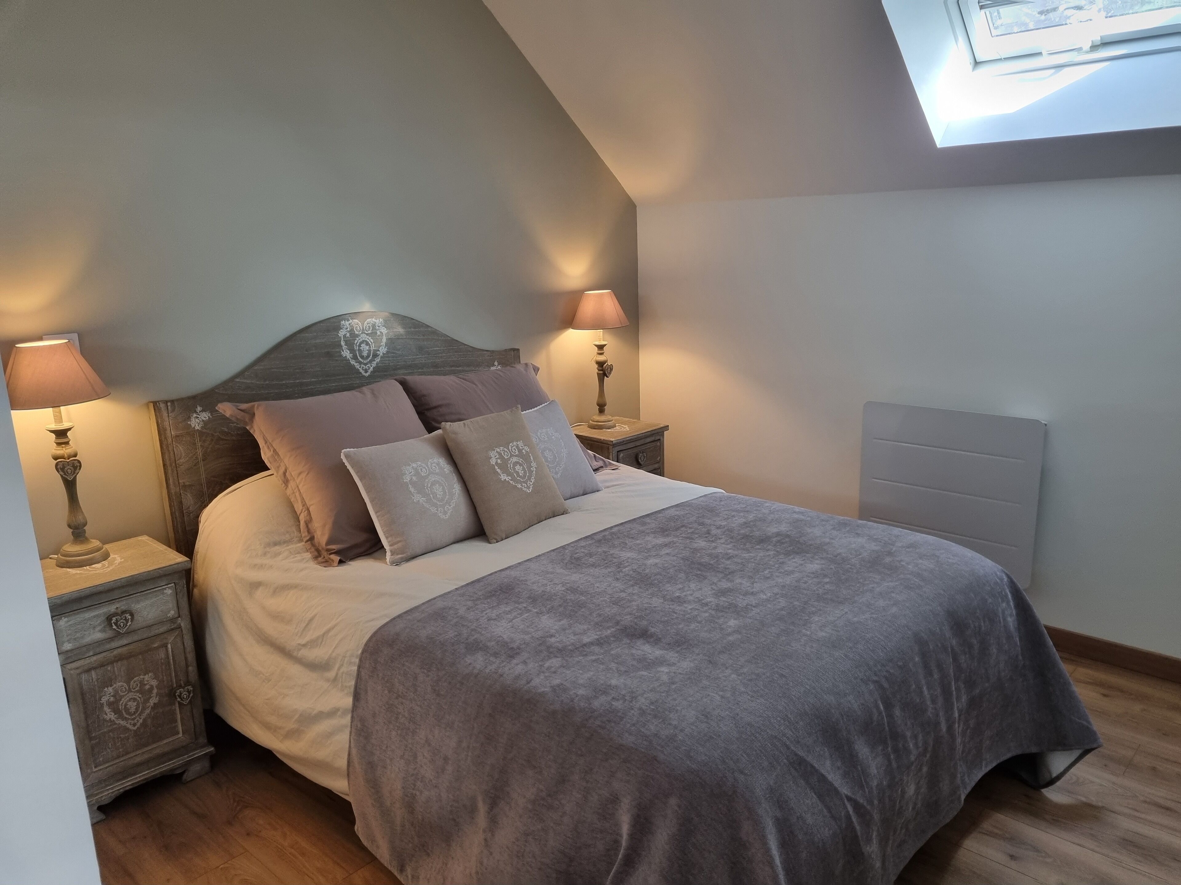 Een slaapkamer met een bed, twee nachtkastjes, een venster en een radiator.