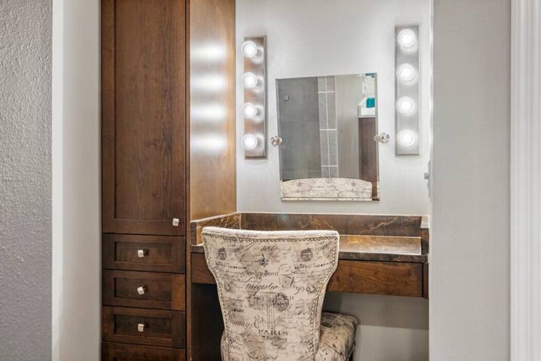 Un tocador con espejo, luces y una silla.