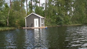 A houseboat with a small deck and a door, surrounded by water and lily pads. - Cozy Tiny Houseboat in the Nature (Hjulvhult)