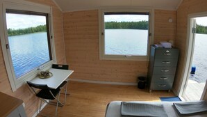 A cabin with wooden walls, a bed, a desk with a chair, and a dresser. - Cozy Tiny Houseboat in the Nature (Hjulvhult)