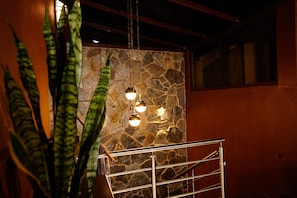 Una escalera con pared de piedra de fondo y lámparas colgantes.