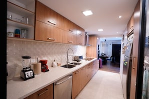 Una cocina moderna con armarios de madera, lavavajillas de acero inoxidable, cafetera y refrigerador.