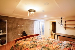 Un dormitorio con una colcha estampada con flores, un escritorio de madera, una silla y un armario.