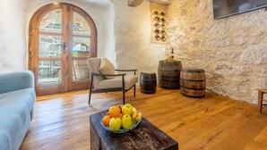 Un intérieur rustique avec un mur en pierre, un plancher en bois, une porte en bois, une chaise, une petite table avec des fruits et des barils.