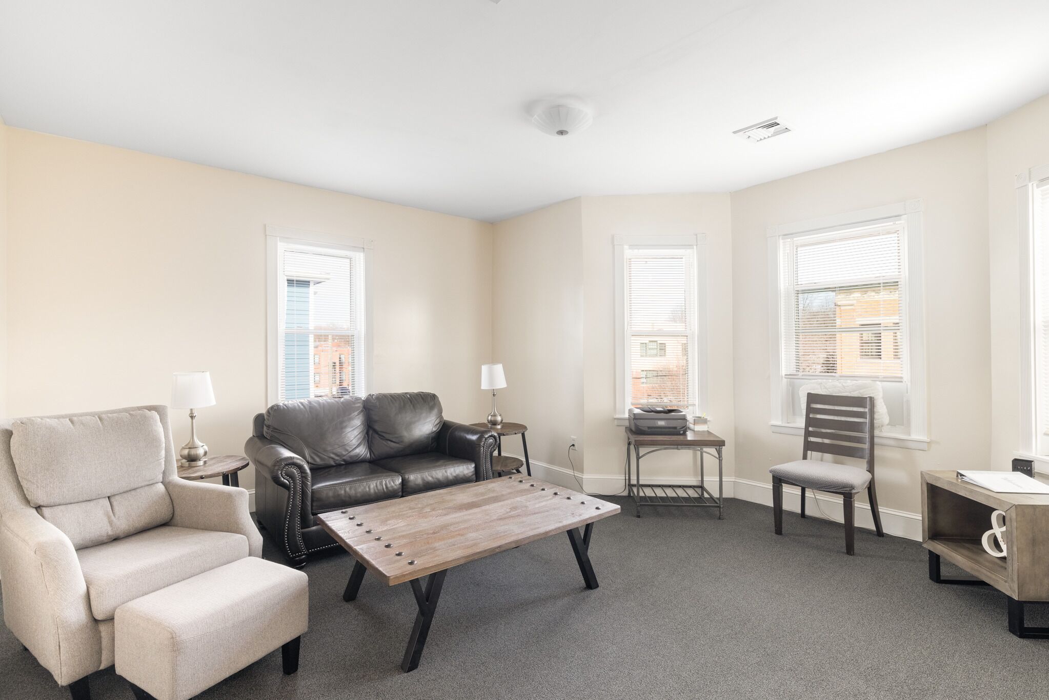 A living room with a sofa, armchair, coffee table, and a small side table with a lamp.