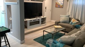 A living room with a flat-screen TV, a sofa, a coffee table, and a pool table.