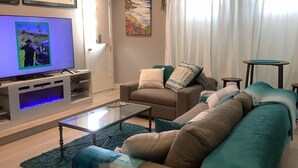 A living room with a television, sofa, coffee table, and a painting on the wall.