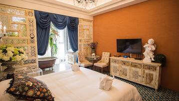 A hotel room with a large bed, a TV, a statue, and a decorative wall.