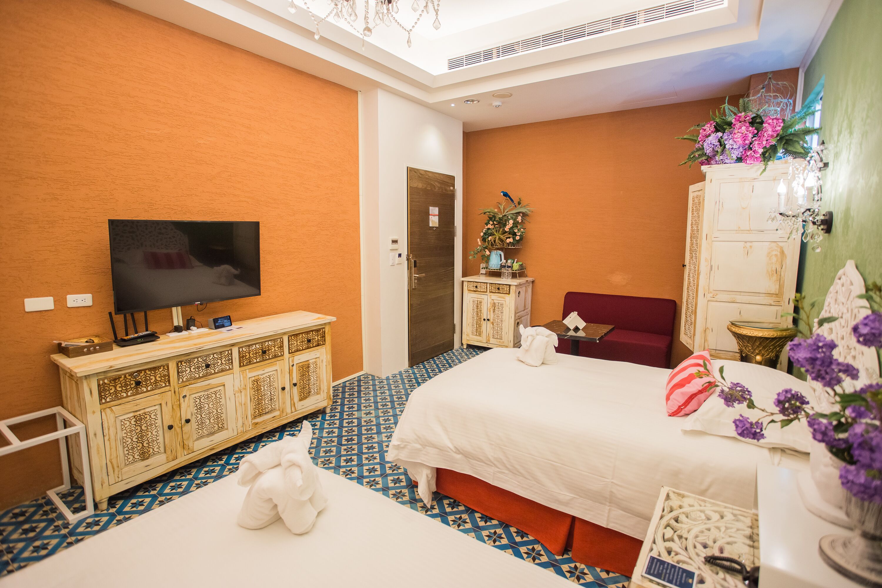 A hotel room with two beds, a television, a cabinet, and a decorative wall.