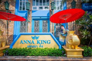 Une enseigne portant le nom «
Anna King
», ornée d’un emblème représentant un lion, le tout entouré de verdure et d’une statue d’éléphant dorée.