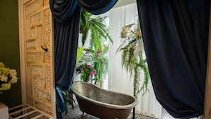 Une salle de bain dotée d’une baignoire îlot, d’un panneau décoratif en bois et offrant une vue sur un jardin intérieur luxuriant.