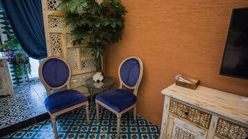 A room with two blue upholstered chairs, a small round table, and a decorative cabinet.