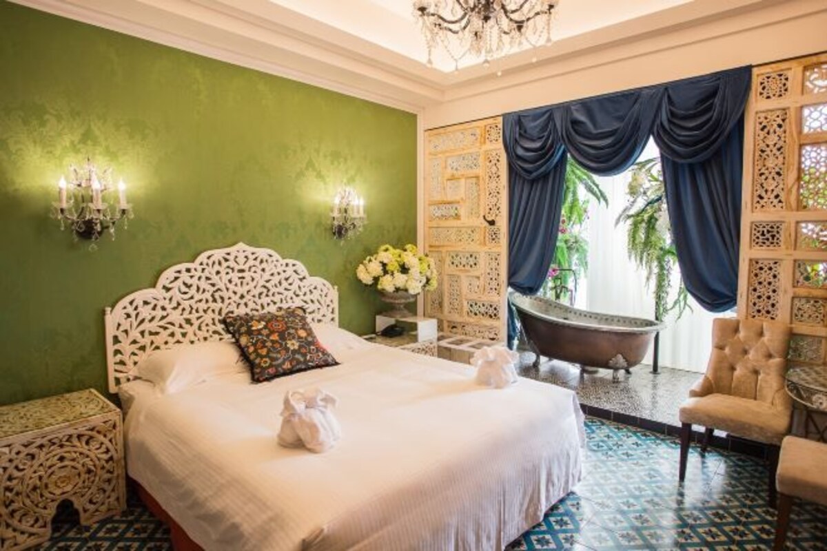 Une chambre avec un grand lit, une baignoire et un fauteuil.