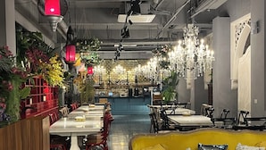 Un restaurant doté d’une longue table à manger, de nombreuses chaises, d’un coin bar et d’un canapé jaune.