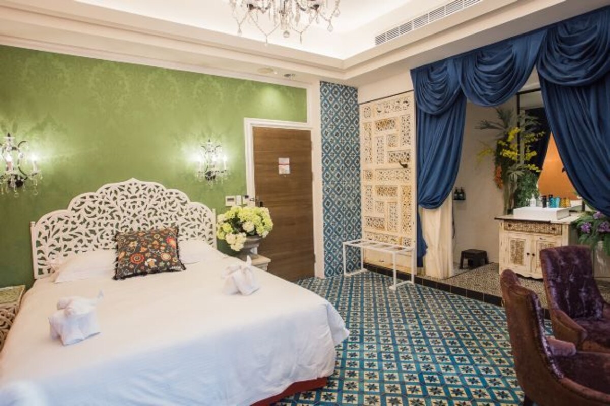 Une chambre d’hôtel avec un grand lit, une petite table, une chaise et un miroir.