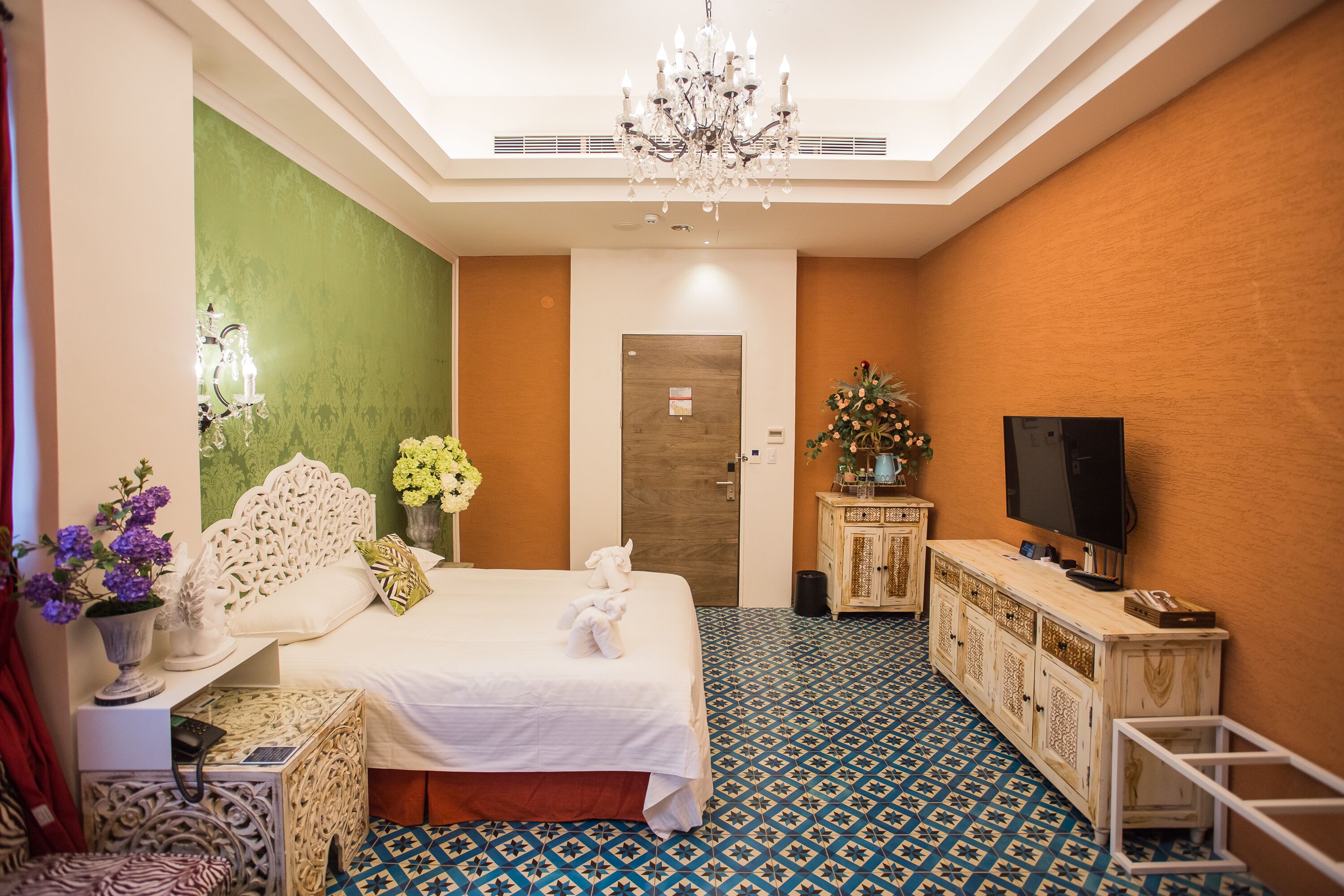 Une chambre d’hôtel avec un lit, une télévision, une armoire et un lustre.