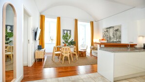 A modern kitchen with a central island, a dining area with wooden chairs, and a large mirror.