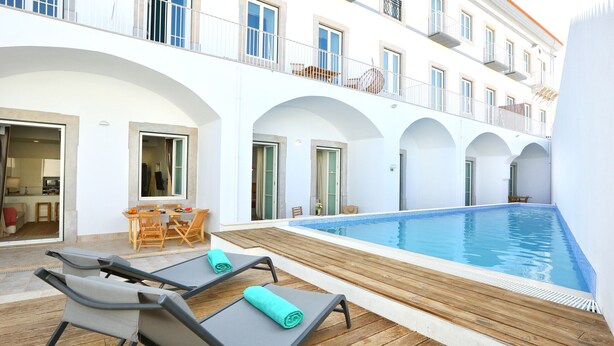 A poolside area with lounge chairs and a wooden deck.