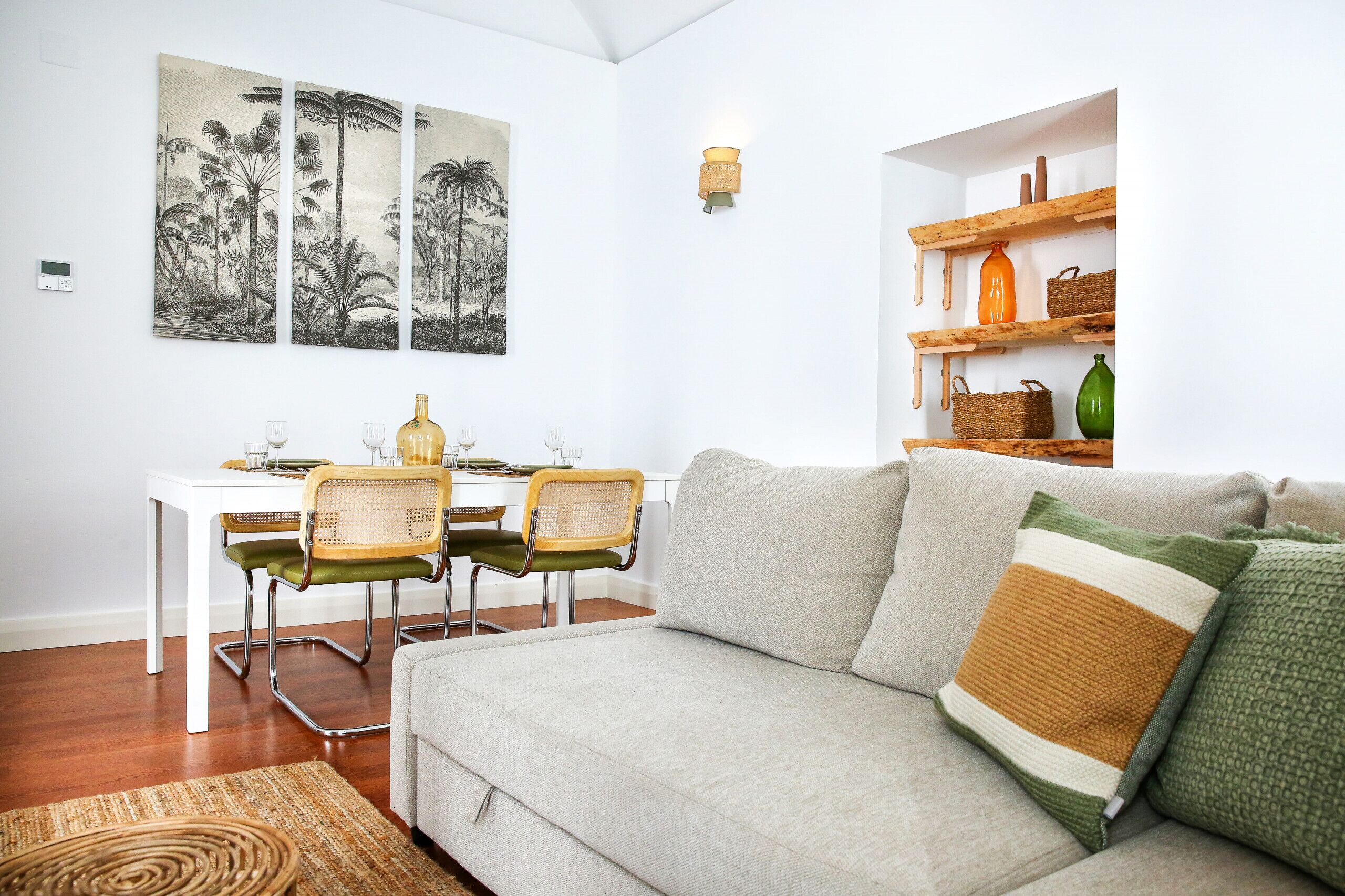 Una sala de estar con sofá, sillas, una mesa de comedor y obras de arte en las paredes.