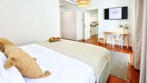 A modern hotel room with a large bed, a desk, and a television mounted on the wall. - Endless Summer Apartment (Faro)