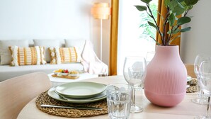 A dining table set with plates, glasses, and a pink vase with a plant. - Endless Summer Apartment (Faro)