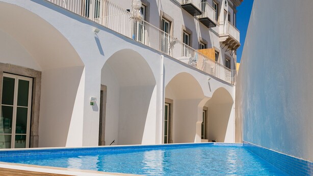 A swimming pool with a wooden deck, white arches, and a balcony with railings. - Endless Summer Apartment (Faro)