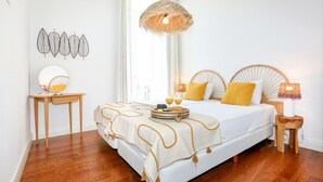 A bedroom with a large bed, bedside tables, a hanging light fixture, and a window. - President Pais Apartment (Faro)